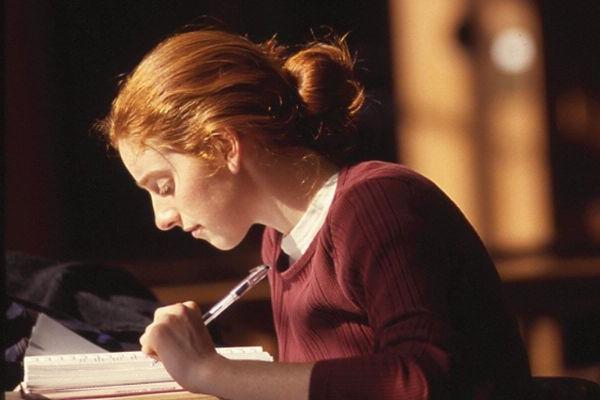 A student at a desk writing in a notebook